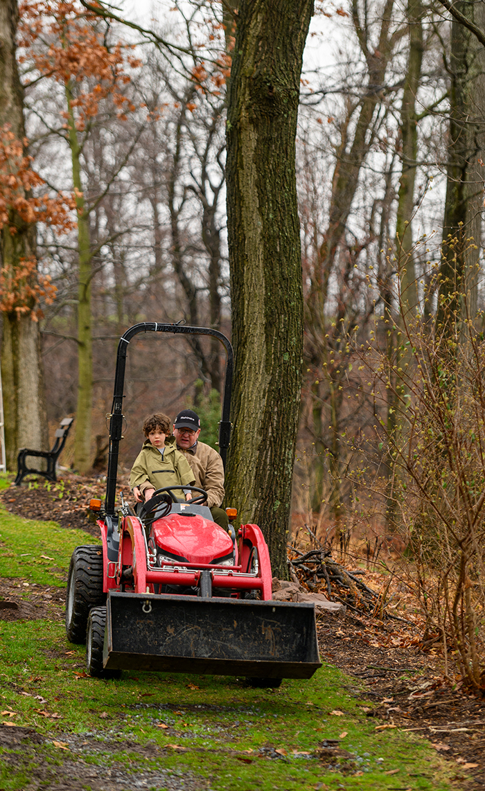 Older man driving a tractor with young child on his lap